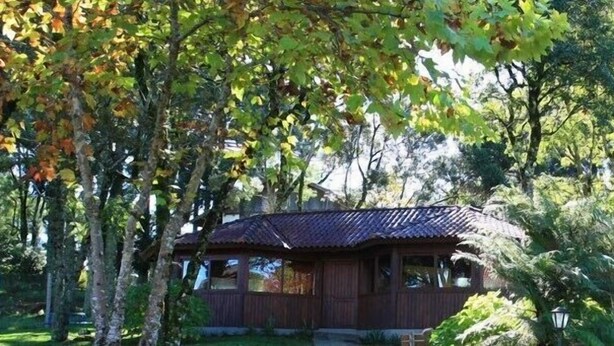 A rustic wooden cabin surrounded by dense foliage. - Pousada Sonnenhof (Gramado)