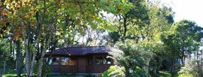 A rustic wooden cabin surrounded by dense foliage. - Pousada Sonnenhof (Gramado)