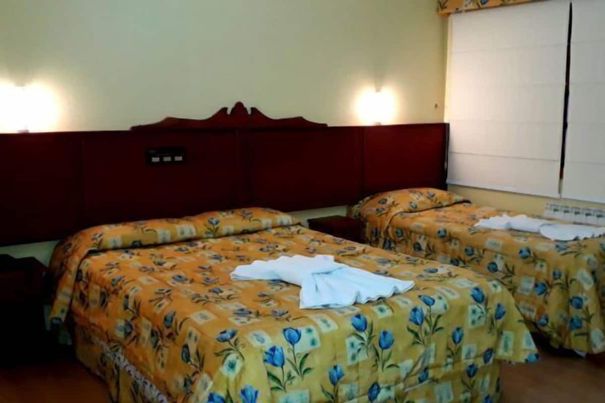 A hotel room with two beds, each with floral bedding and white towels.