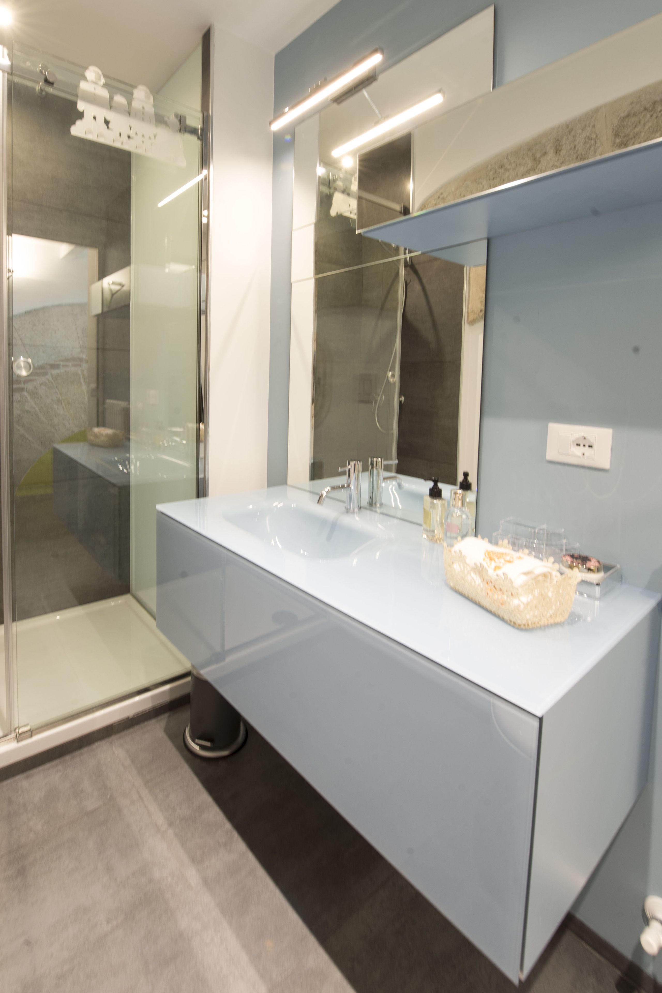 A modern bathroom with a large sink, a glass shower enclosure, and a mirror above the sink.
