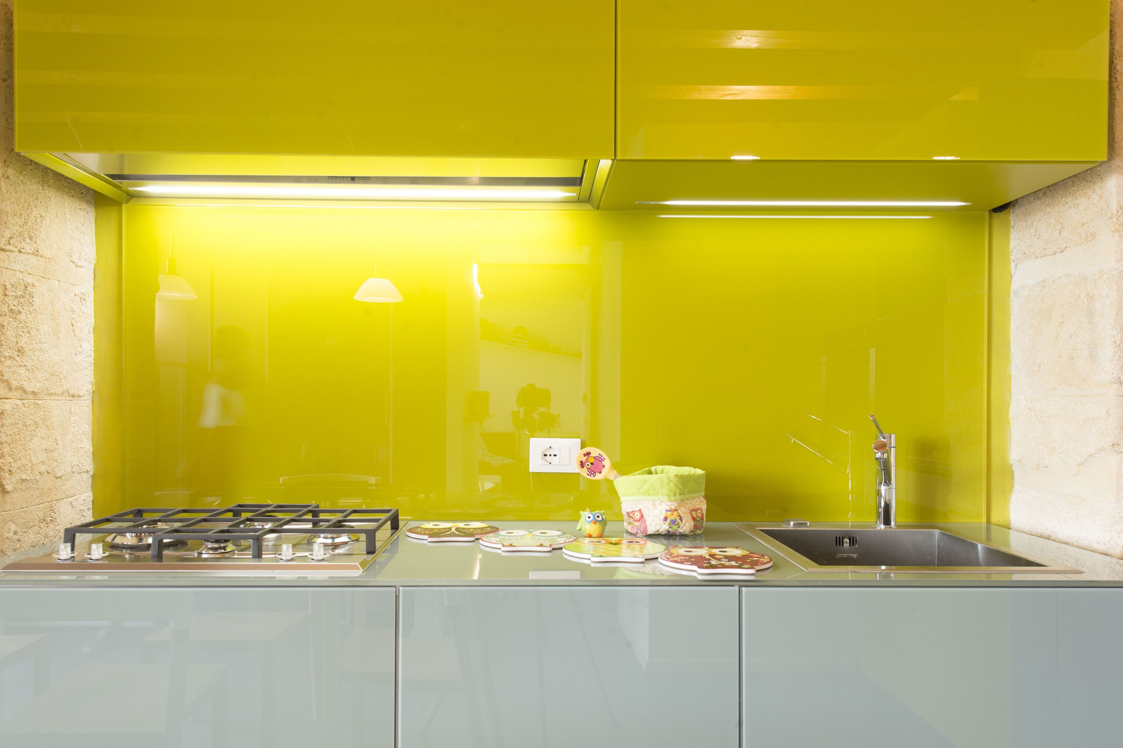 A kitchen with a gas stove, a sink, and a bright yellow backsplash.