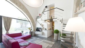 Ein modernes Wohnzimmer mit einem rosa Sofa, einem Fernseher und einer Treppe, die in einen oberen Bereich führt.