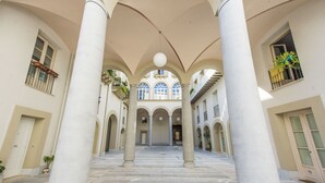 Ein weitläufiger Innenhof mit Säulen, Bögen und einer zentralen offenen Fläche.