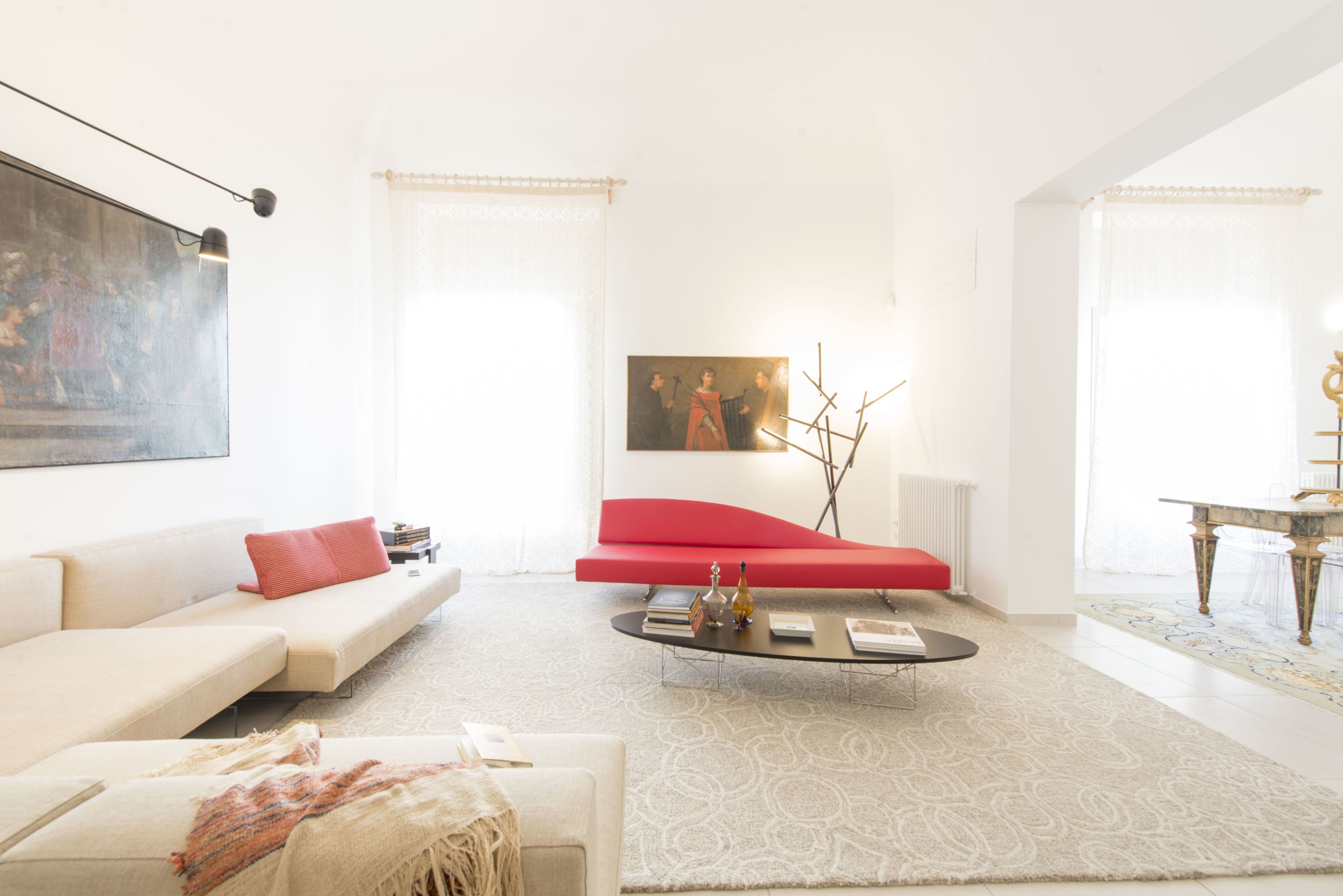 A modern living room with a white sofa, red accent chair, and a coffee table.