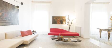 A modern living room with a white sofa, red accent chair, and a coffee table.