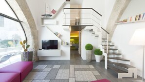 Ein modernes Wohnzimmer mit Flachbildfernseher, einer Treppe und einem Bücherregal.