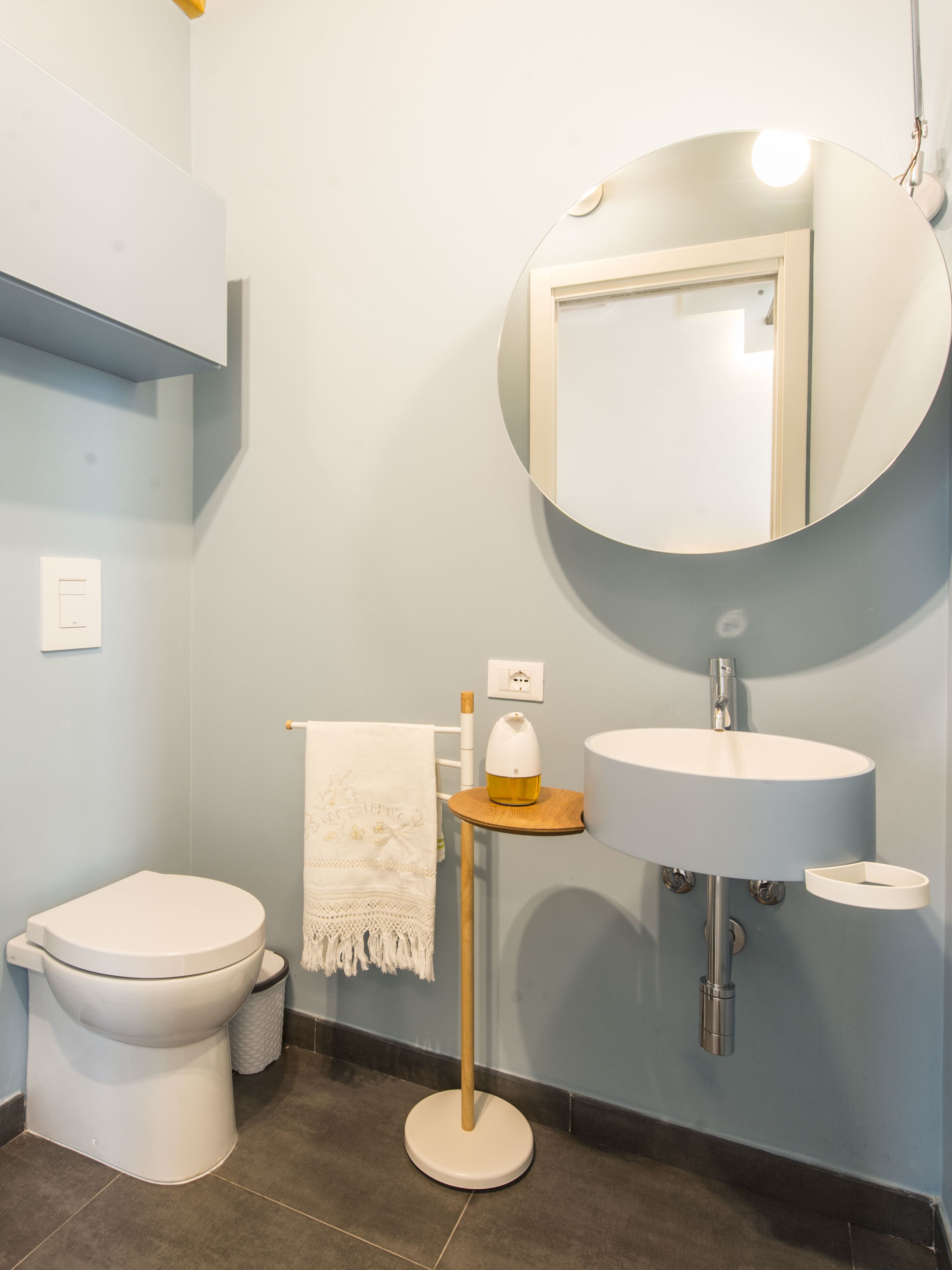 Een moderne badkamer met toilet, wastafel en ronde spiegel.