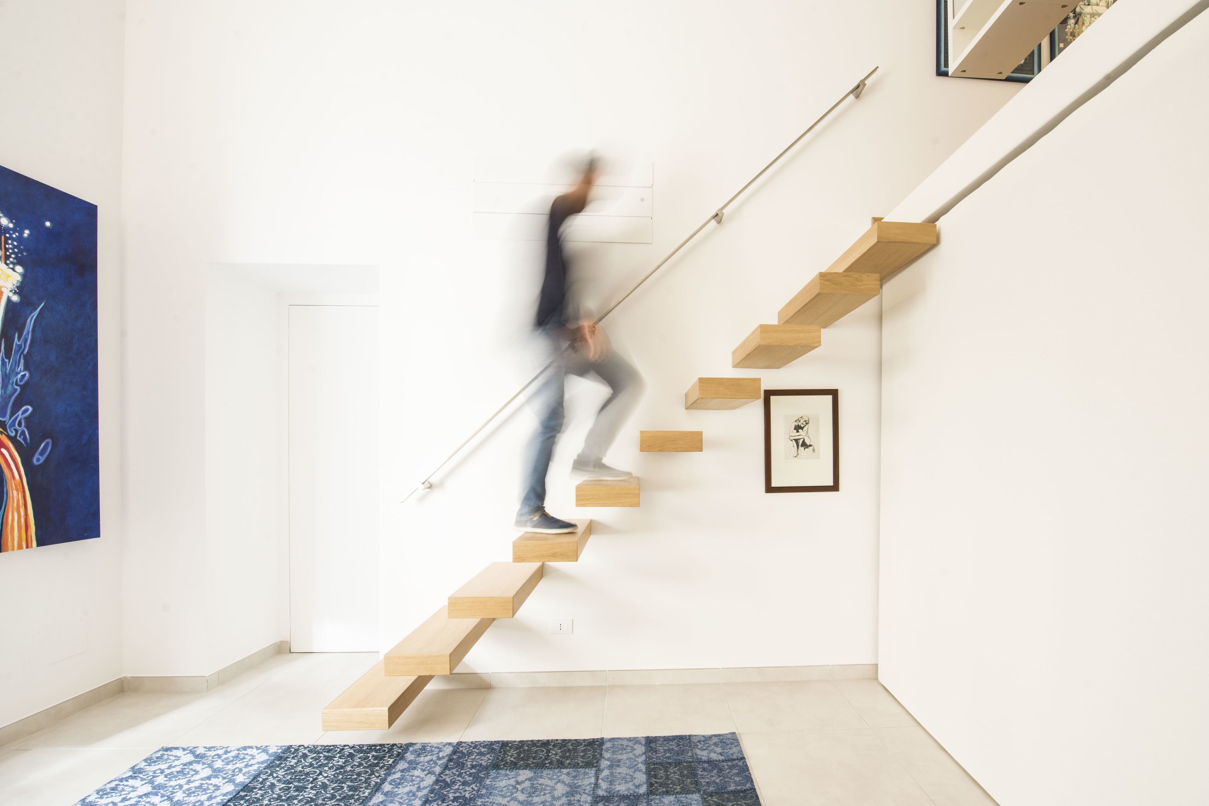 A modern staircase with wooden steps and a handrail, leading to a higher floor.