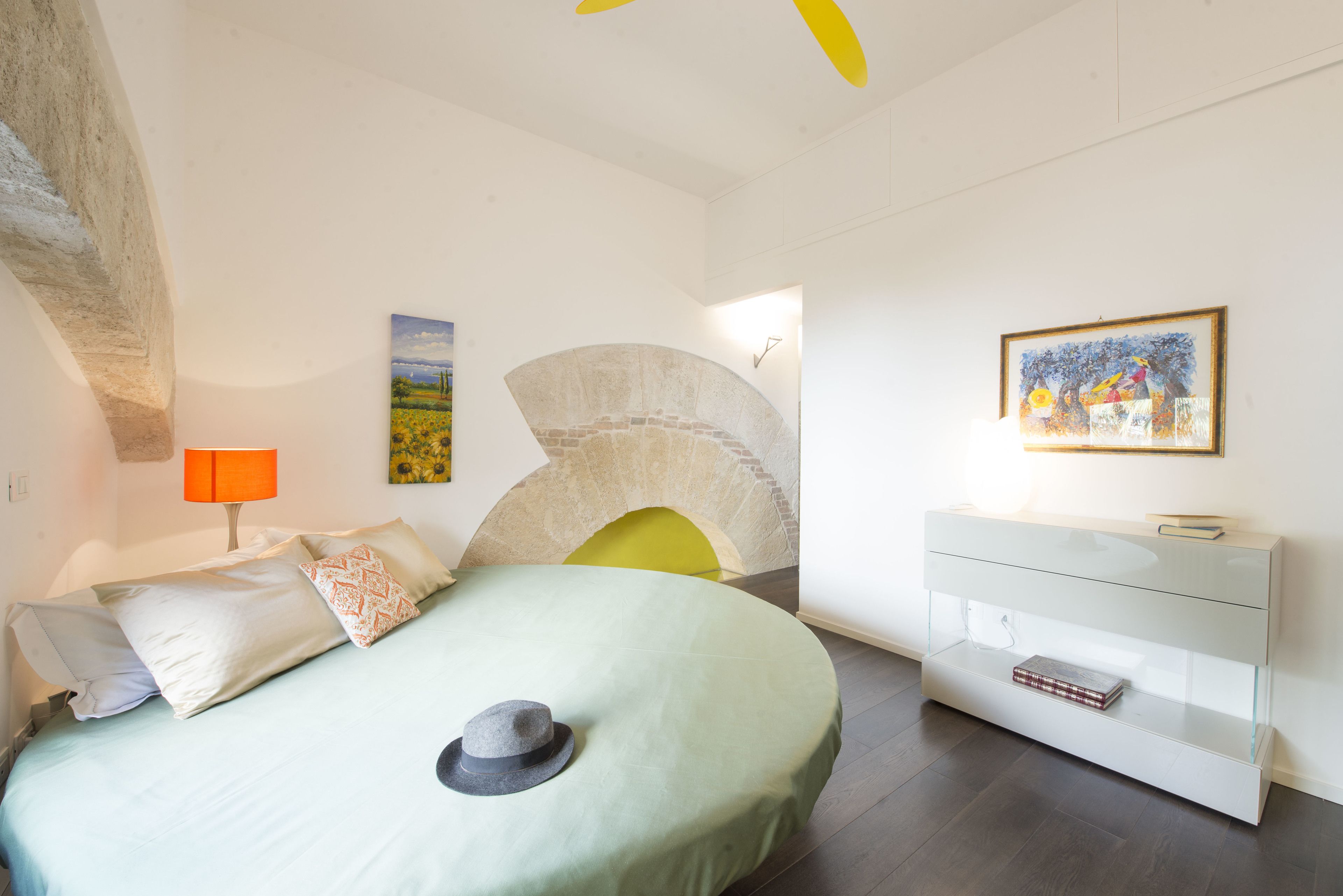 Une chambre à coucher moderne avec un lit, une table de chevet, une lampe, une cheminée et un tableau au mur.
