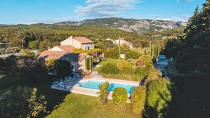 Eine Villa mit Swimmingpool, umgeben von üppigem Grün und Hügeln im Hintergrund.