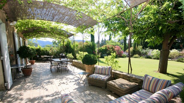 Eine Terrasse im Freien mit Korbmöbeln, einem Tisch und Stühlen.