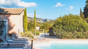 Ein Poolbereich mit Liegestühlen, einer gefliesten Terrasse und Blick auf eine Berglandschaft.