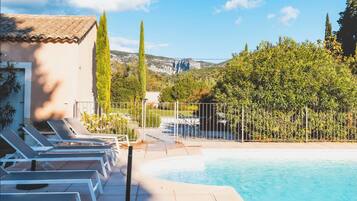 Een buitenzwembad, een verwarmd zwembad, ligstoelen bij het zwembad