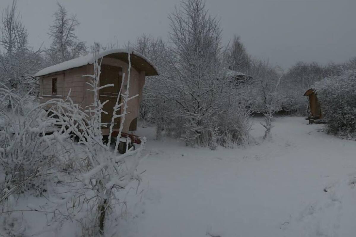 A snow-covered landscape with a wooden cabin structure.