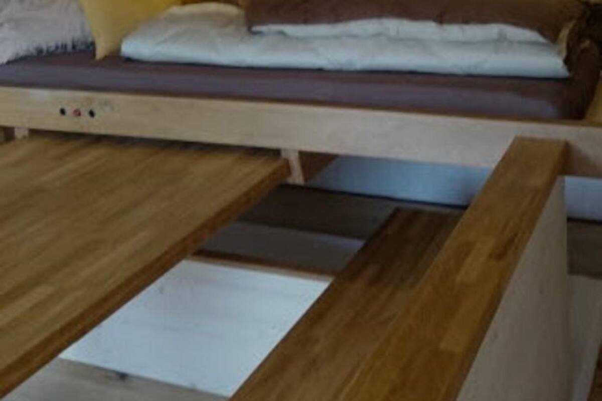 A bunk bed with a wooden frame and a mattress on the lower bunk.