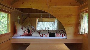 A cozy cabin with a curved wooden ceiling, a bench with cushions, and a central table. - Schaeferwagenhotel-Campsite (Sulzfeld)