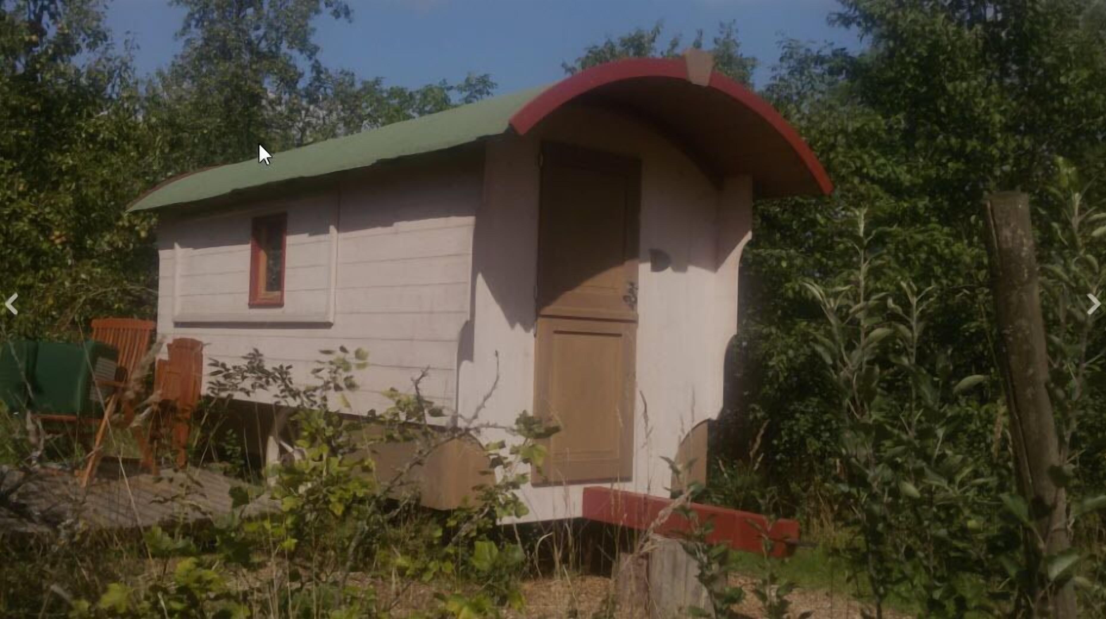 Ett litet hus i en våning med ett grönt tak och en röd ytterdörr.