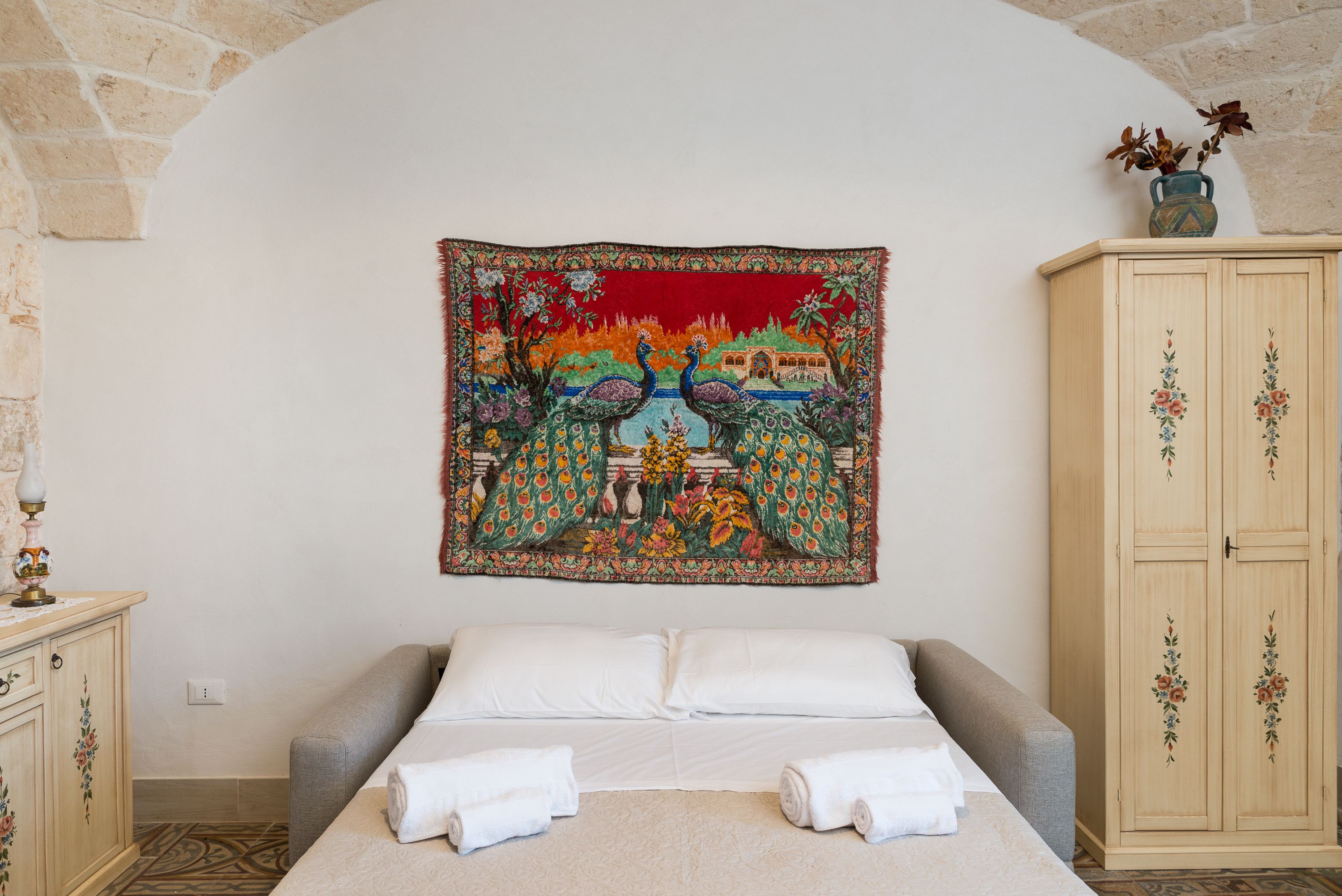 Une chambre à coucher avec un lit, une tapisserie, une armoire et une lampe.