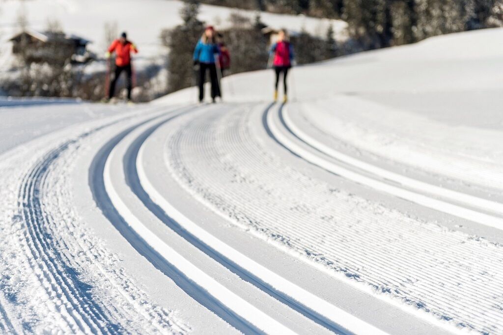A snowy road with tire tracks curving into the distance.