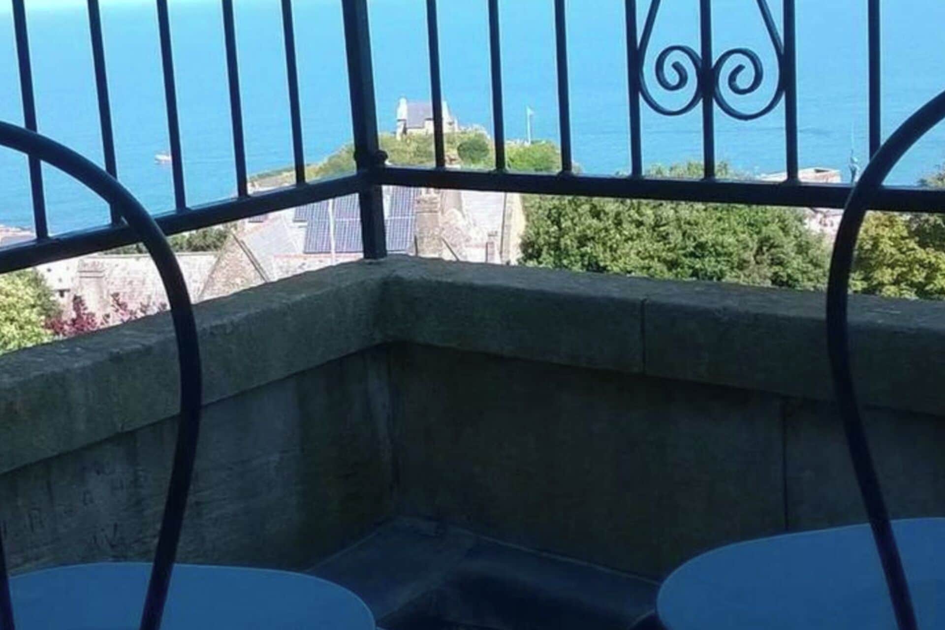 A balcony with a view of the sea and buildings.