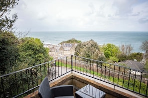 A balcony with a view of the sea and a historic building.