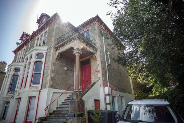 A corner building with a red door, white-framed windows, and a balcony. - Sea View Ultimate Boutique Escape! (Ilfracombe)