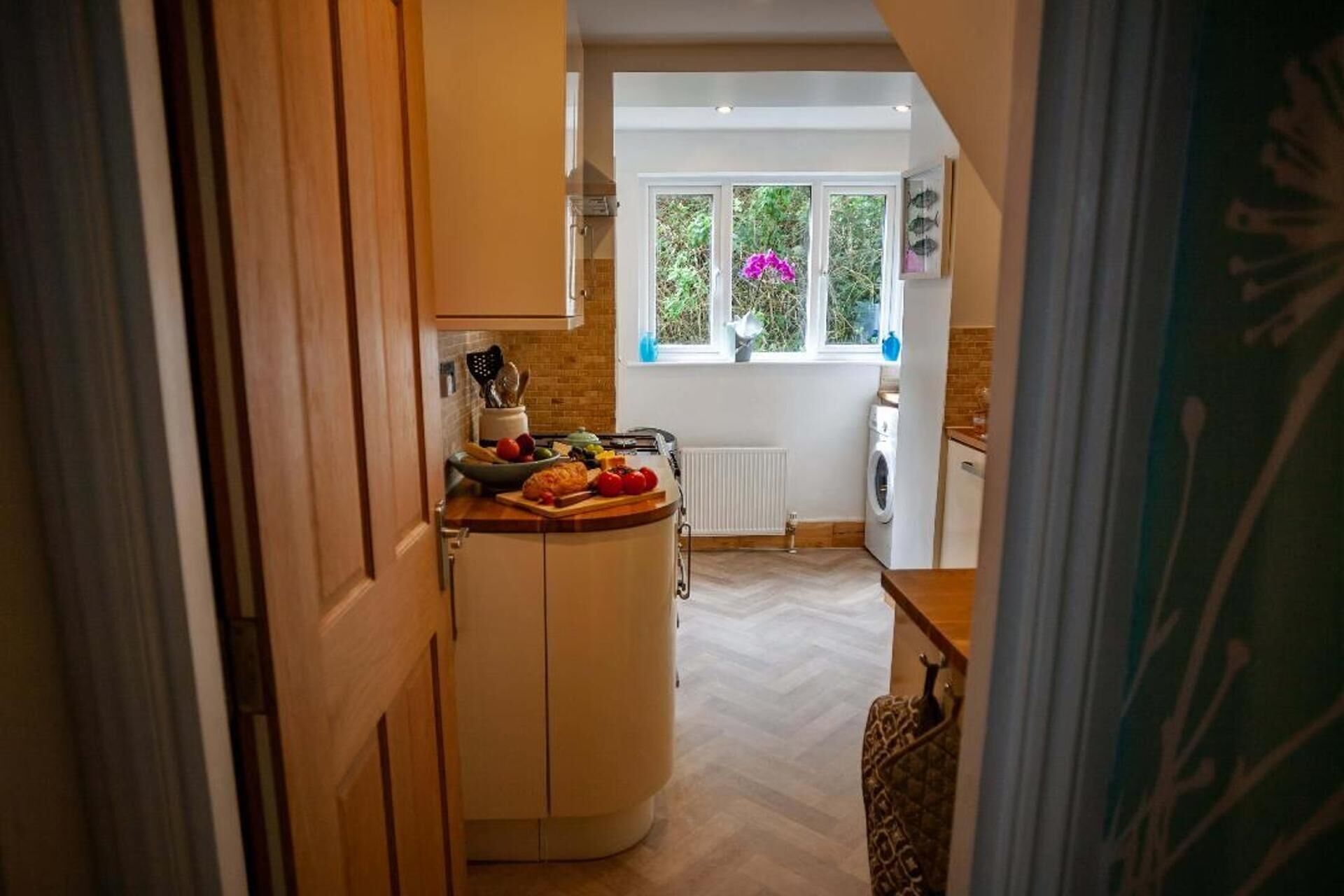 A kitchen with a wooden countertop, a window with a view of greenery, and a radiator.