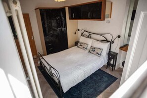 A bedroom with a bed, a wardrobe, a nightstand, and a wall-mounted shelf. - Sea View Ultimate Boutique Escape! (Ilfracombe)