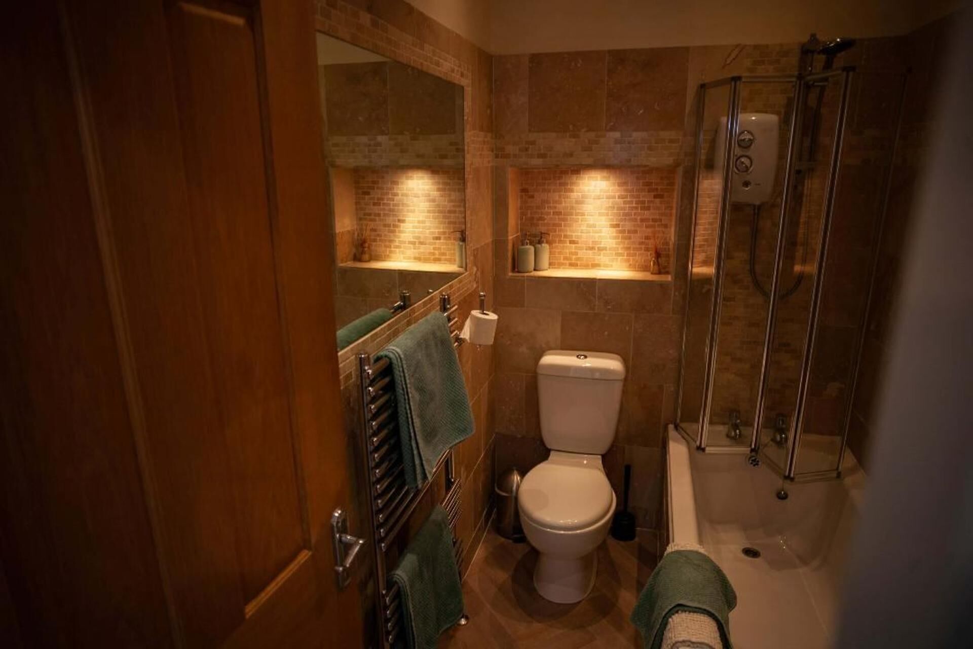 A bathroom with a toilet, a shower, a towel rack, and a mirror.