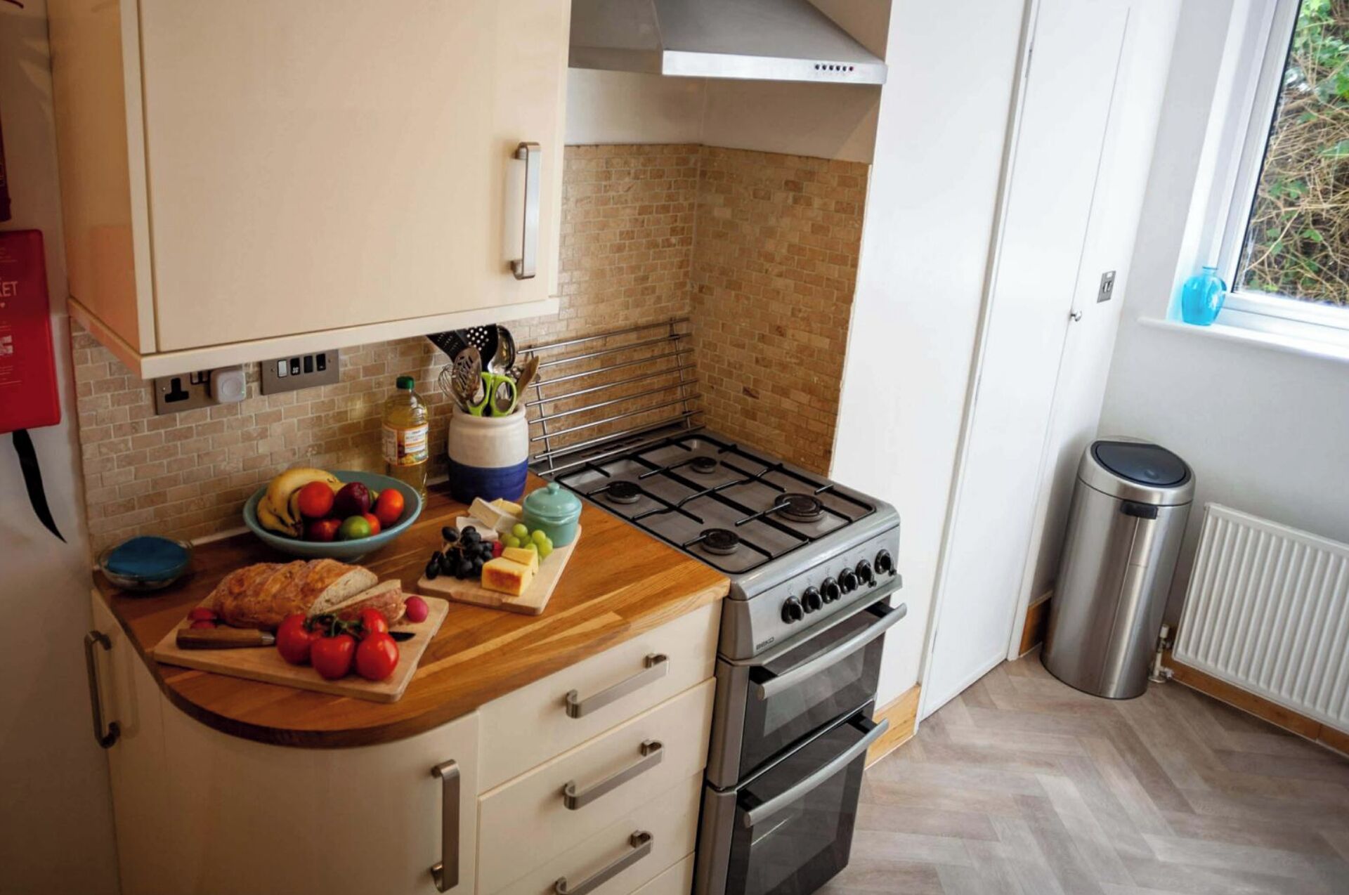 A kitchen with a gas stove, oven, and a window with a view of greenery.