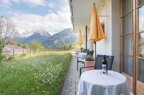 A terrace with tables and chairs, a bottle of wine, and a view of snow-capped mountains. - Pension Chalet Berkana (Hasliberg Reuti)