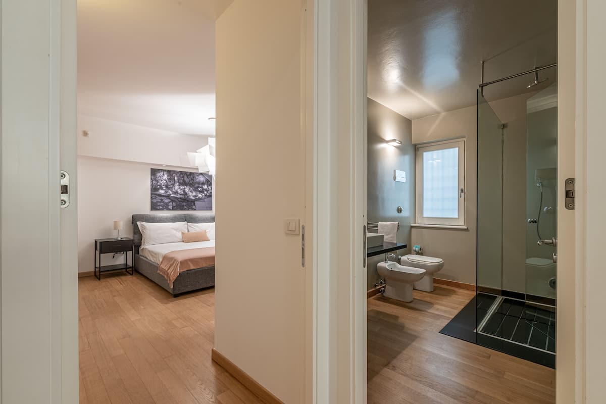 A bedroom with a bed, bedside table, and a painting on the wall.