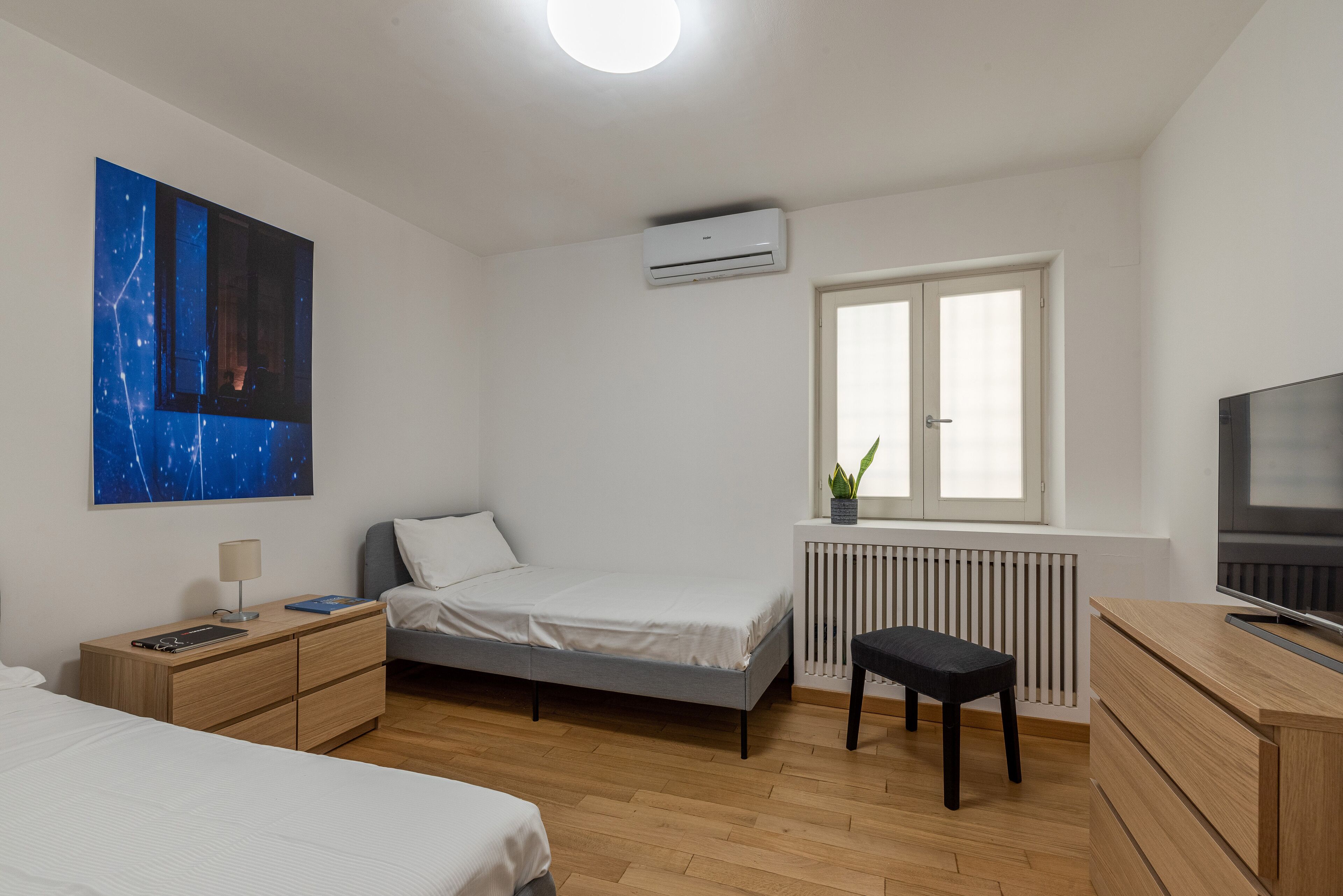 A modern bedroom with a bed, bedside table, desk, and a radiator.