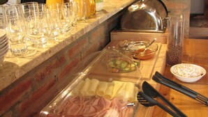 A buffet setup with various food items, utensils, and a wine rack. - Pension Abertham (Abertamy)