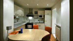 A modern kitchen with white cabinets, a central island with seating, and overhead lighting. - Pension Abertham (Abertamy)