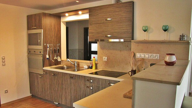 A modern kitchen with wooden cabinets, stainless steel appliances, and a built-in oven. - Pension Abertham (Abertamy)