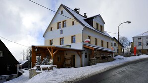 A two-story building with a covered entrance and a sign indicating a restaurant. - Pension Abertham (Abertamy)