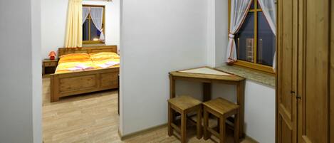 A bedroom with a wooden bed, a desk with two chairs, and a window with curtains.