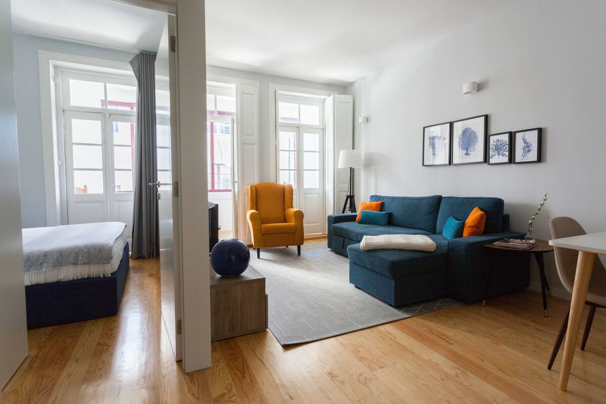 A modern living room with a sofa, armchair, and a dining table.