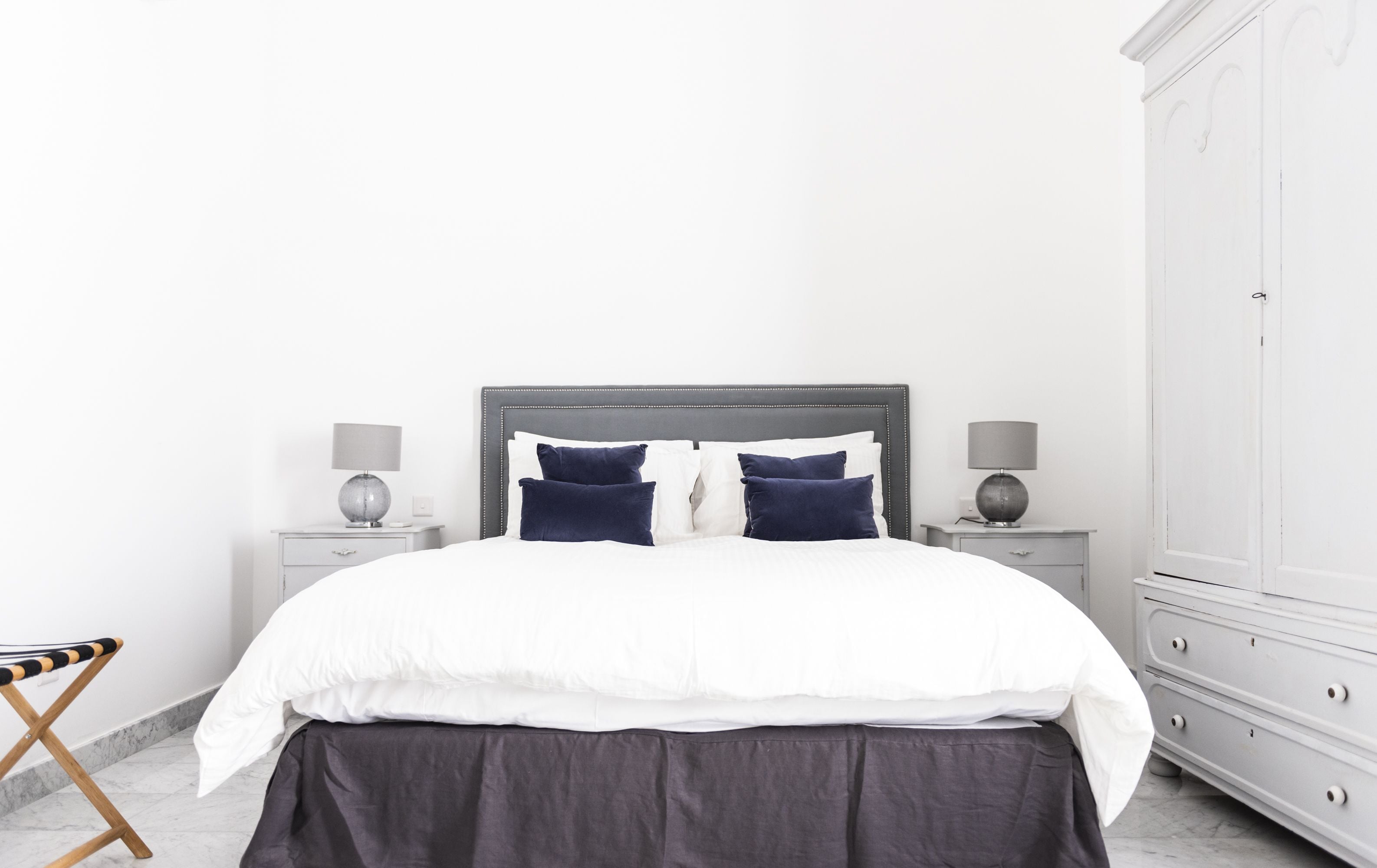 Une chambre à coucher bien rangée, avec un grand lit, deux tables de chevet et une armoire.