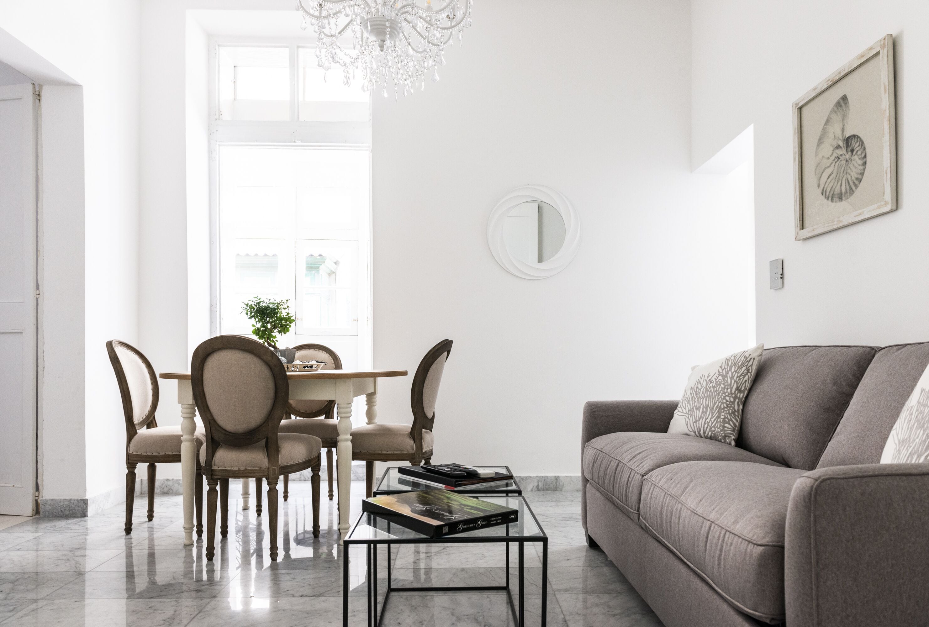 A modern living room with a sofa, a dining table with chairs, and a coffee table.