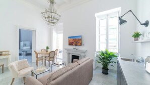 Amplia sala de estar con sofá, sillas, una mesa de centro, chimenea y comedor.