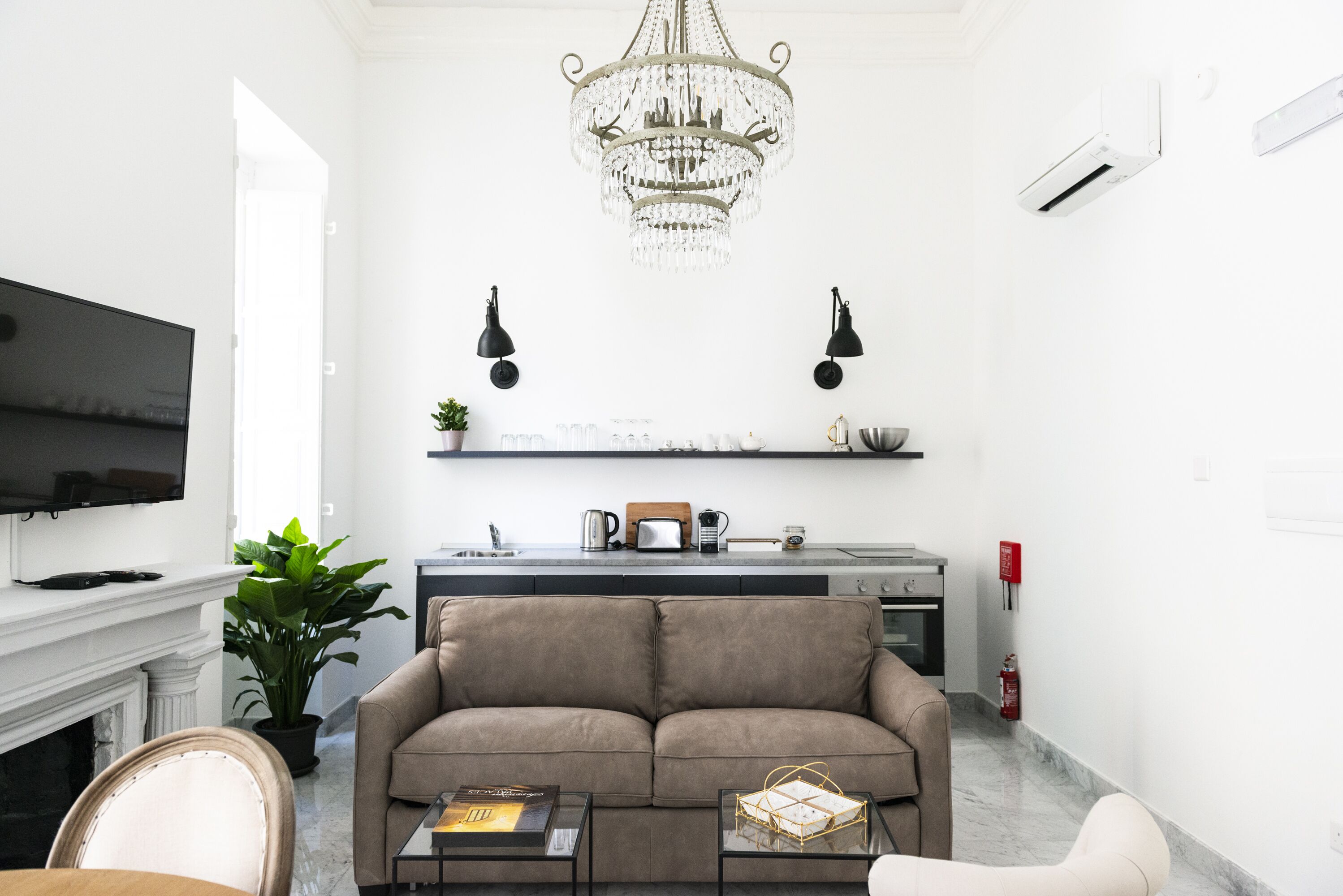 A living room with a sofa, coffee table, TV, fireplace, and a chandelier.