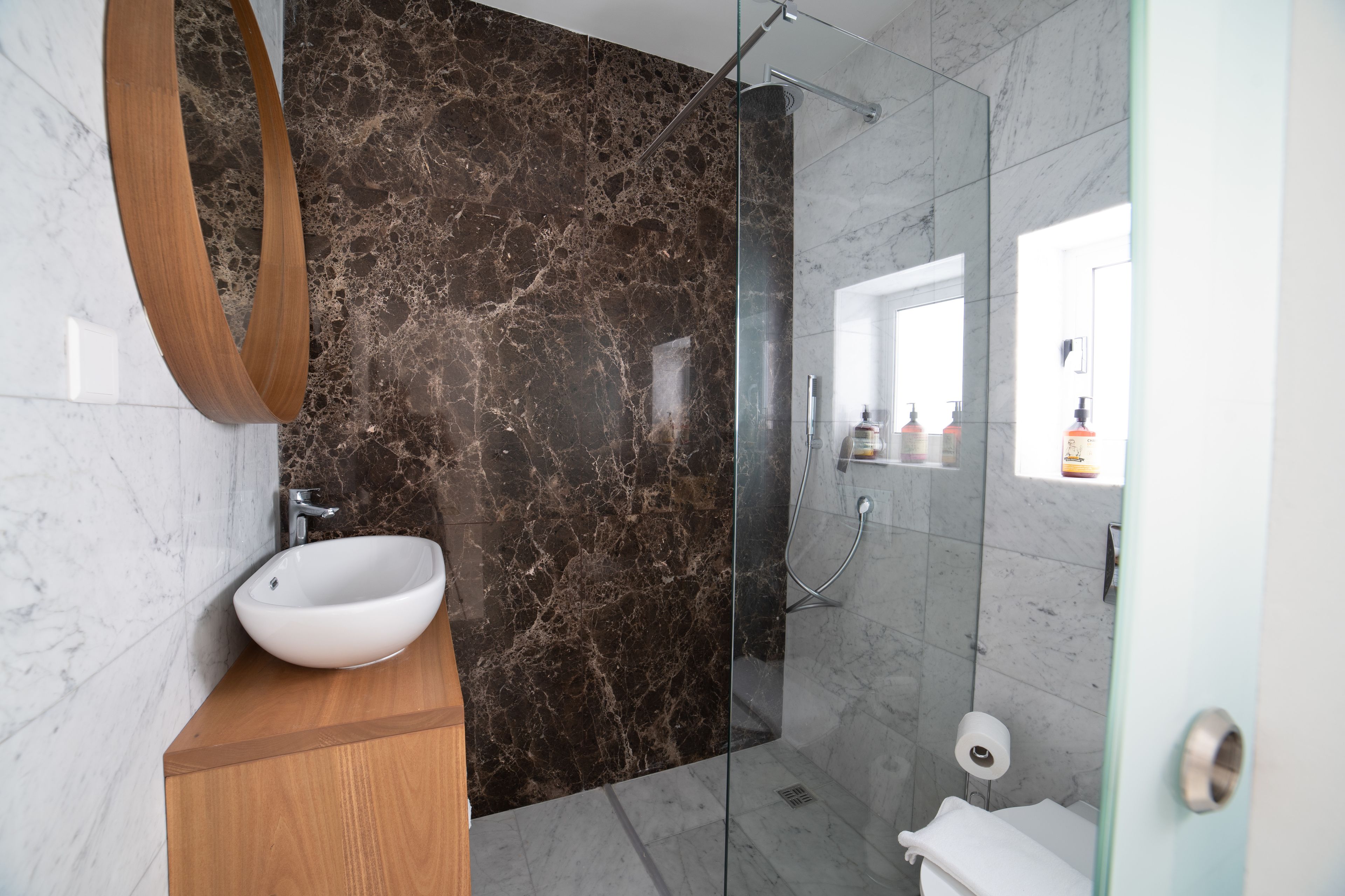 Une salle de bain moderne avec un meuble-lavabo en marbre, une cabine de douche en verre et des toilettes.