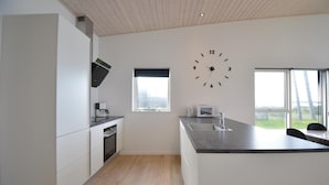A modern kitchen with a built-in oven, microwave, and sink. There is a large window providing a view of the outdoors. - Gorgeous home in Ebeltoft with WiFi (Ebeltoft)