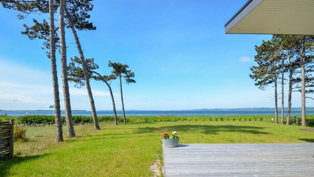 A wooden deck leading to a grassy area with a view of the sea and distant hills. - Gorgeous home in Ebeltoft with WiFi (Ebeltoft)