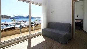 A room with a large window offering a view of a cruise ship and marina. - Ufuk Hotel (Çeşme)