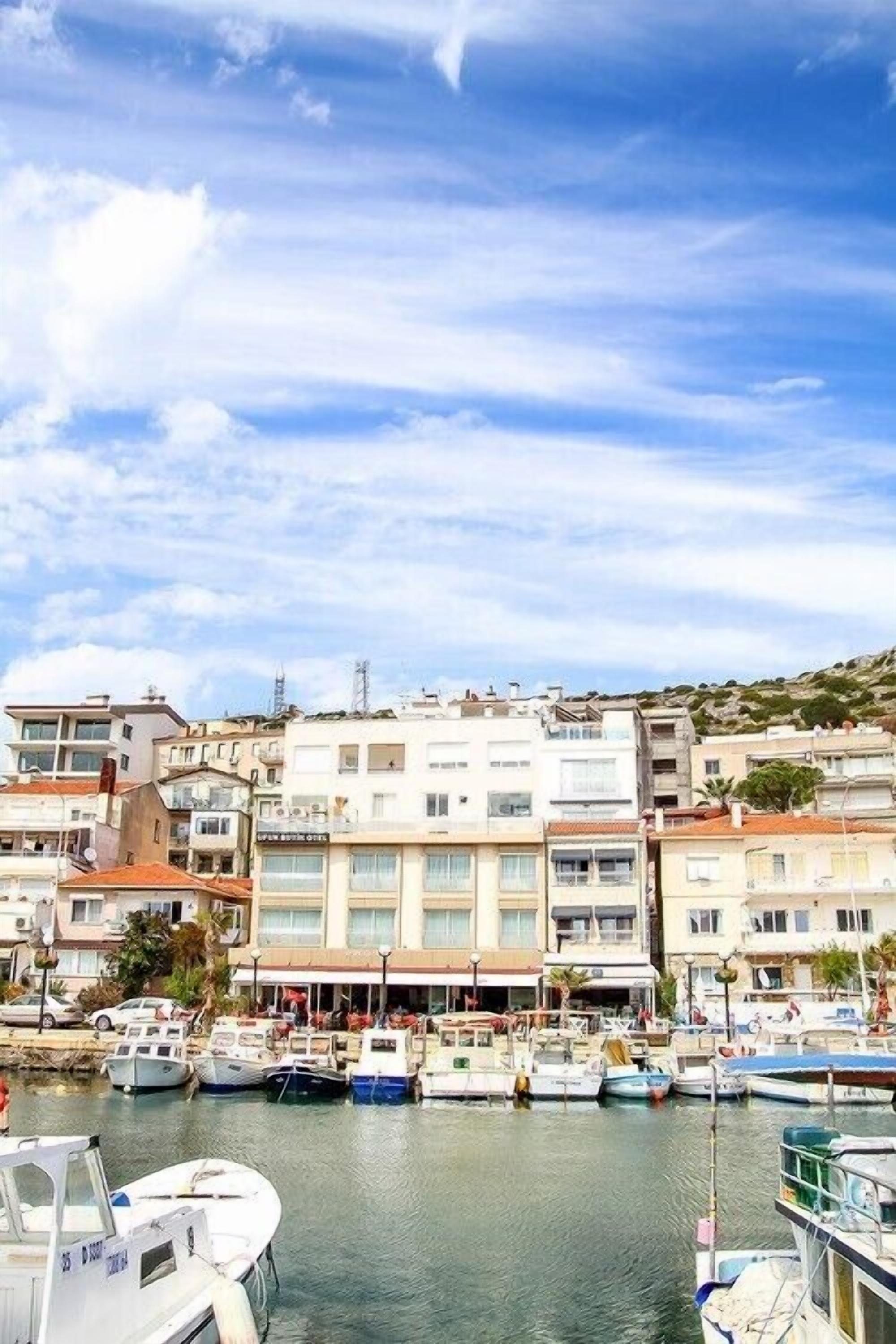 A marina with multiple boats docked, surrounded by multi-story buildings with commercial establishments on the ground floor.