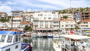 A marina with multiple boats docked, a hotel named "UFUK RUTUK HOTEL" in the background, and a flag on a flagpole. - Ufuk Hotel (Çeşme)