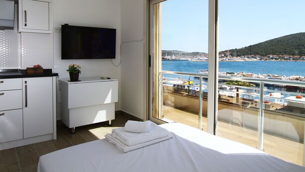 A hotel room with a balcony overlooking a marina and a hilly landscape. - Ufuk Hotel (Çeşme)
